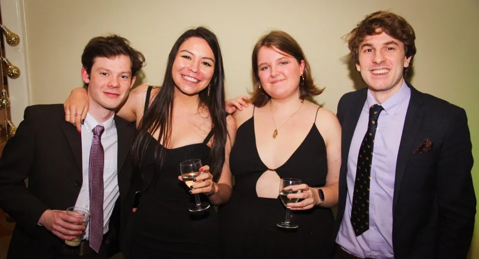 Quattro persone sono insieme a un evento al King's College e indossano abiti formali.