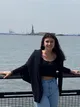 Estudiante sonriente en el puerto de Nueva York con la Estatua de la Libertad al fondo