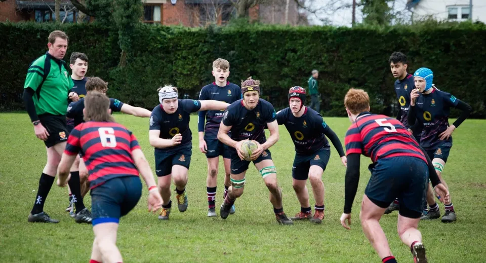 Un gruppo di giocatori di rugby indossa maglie diverse durante una partita sul campo della Royal School.