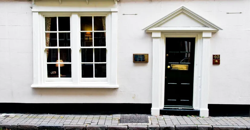 Un edificio bianco con una porta in legno nera e una grande finestra nel campus del Greene's College Oxford.