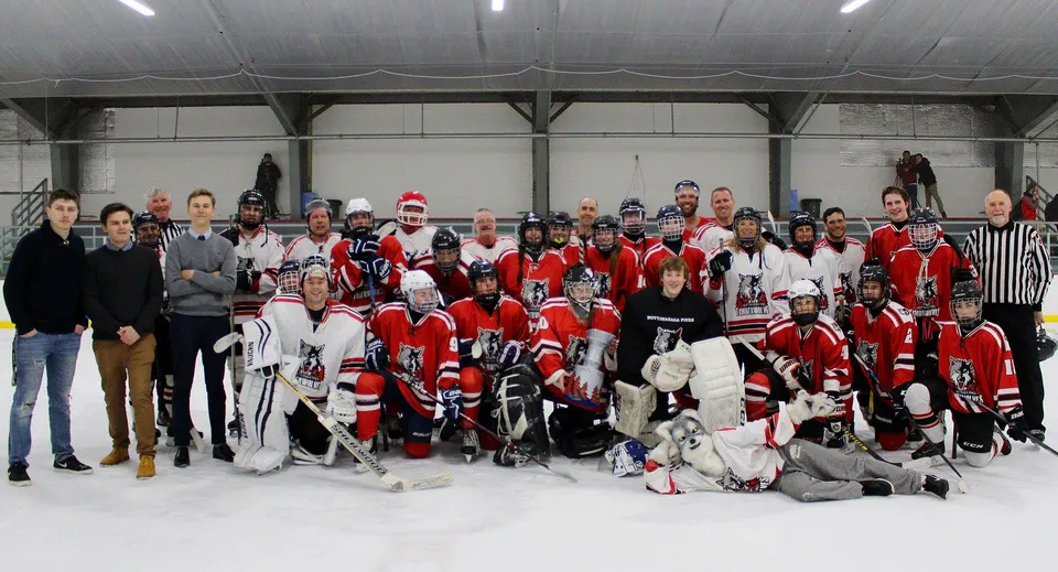 Un gruppo di studenti e studentesse della Nottawasaga Pines Secondary School sta in divisa da hockey sulla pista da ghiaccio al coperto.