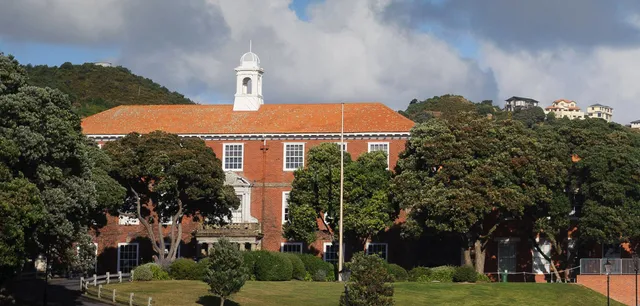 L'edificio storico in mattoni con campanile bianco si trova nel campus del Scots College, circondato da alberi e da un prato curato.