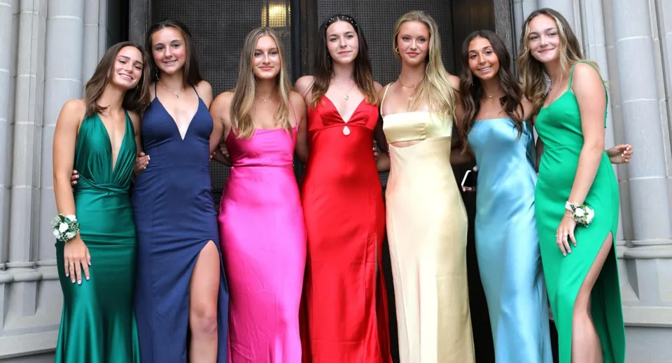 Un gruppo di giovani donne in abiti colorati sta davanti a un edificio in pietra nel campus della Mercersburg Academy.