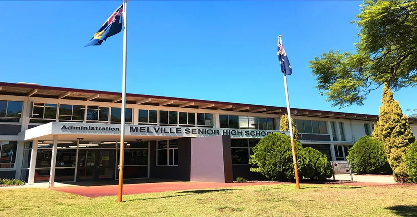 L'ingresso principale della Melville Senior High School con la bandiera australiana e del Western Australia in primo piano e alberi sullo sfondo.