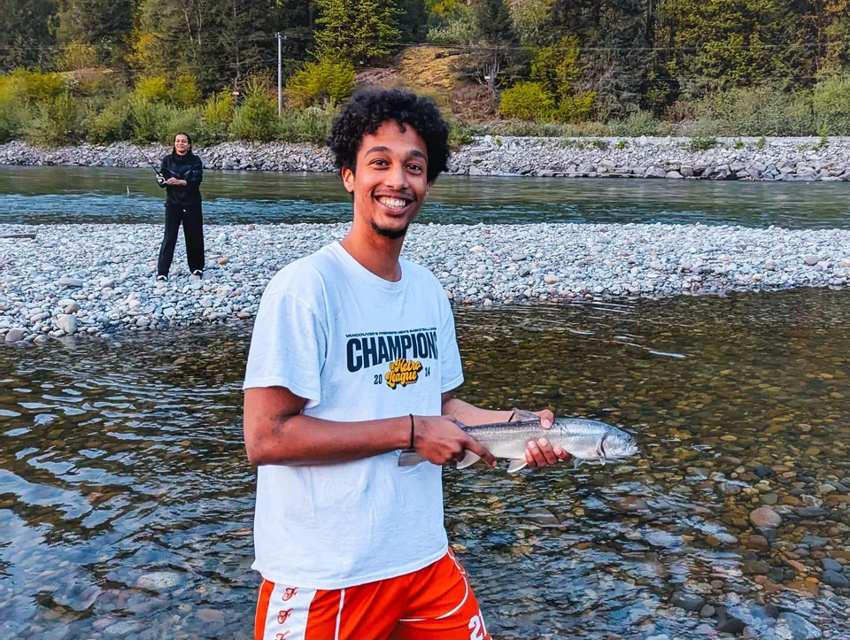 Uno studente della Pioneer School Port Coquitlam tiene in mano un pesce nelle acque basse di un fiume.