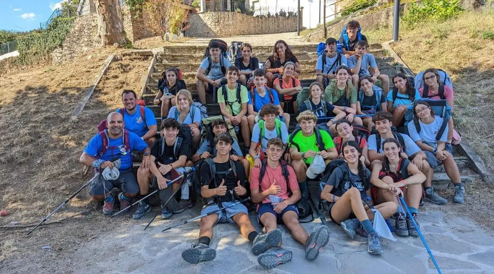 Un gruppo di studenti e studentesse è seduto sulle scale esterne del campus del Colegio Esclavas davanti a muri in pietra e aree verdi.