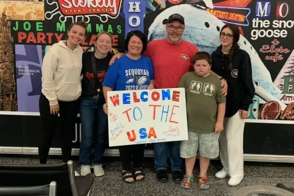 Grupo de personas posa junto sosteniendo un cartel donde pone Welcome to the USA