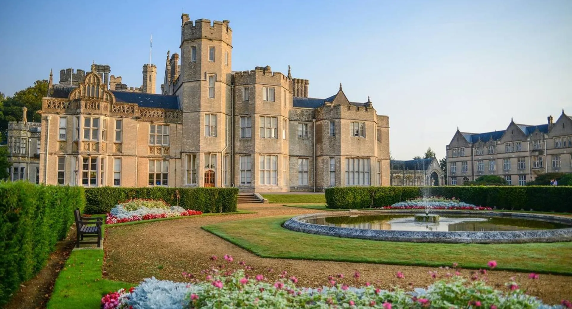 Il castello della Canford School è circondato da un giardino ben curato con una fontana e aiuole fiorite.