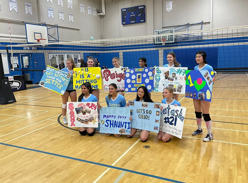Un gruppo di studentesse della Seaquam Secondary School tiene striscioni colorati sul campo da basket.