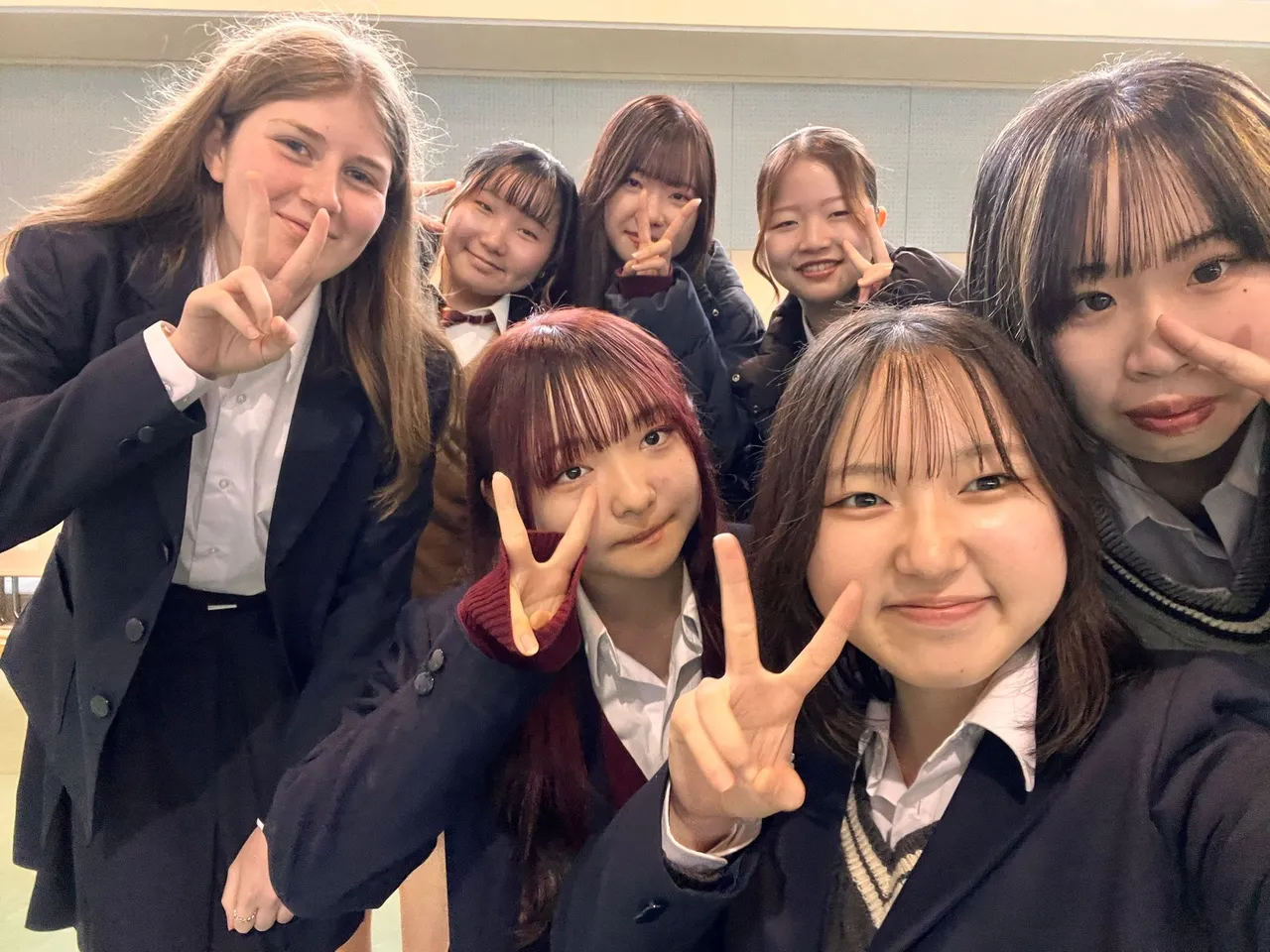 Ragazze in divisa scolastica giapponese si scattano un selfie col segno della pace