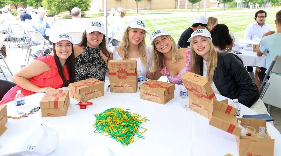 Un gruppo di studentesse della Greensboro Day School all'aperto attorno a un tavolo con in mano delle scatole di cartone.