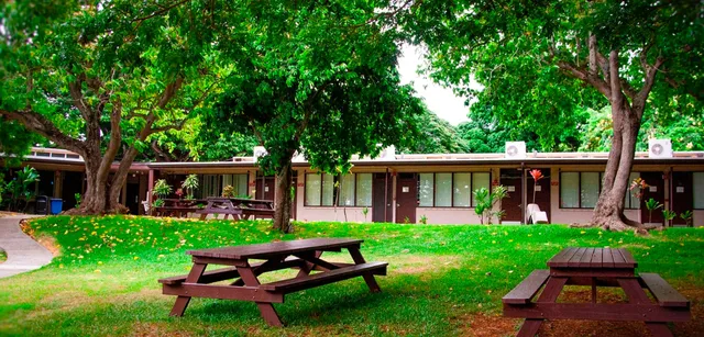 L'area picnic verde nel campus della Trinity Christian School con tavoli e panche di legno sotto gli alberi.