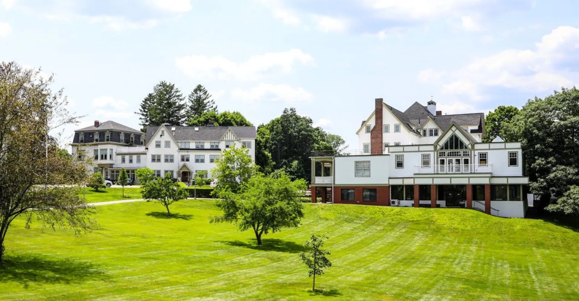 Un prato verde davanti a diversi edifici storici nel campus della Walnut Hill School for the Arts.