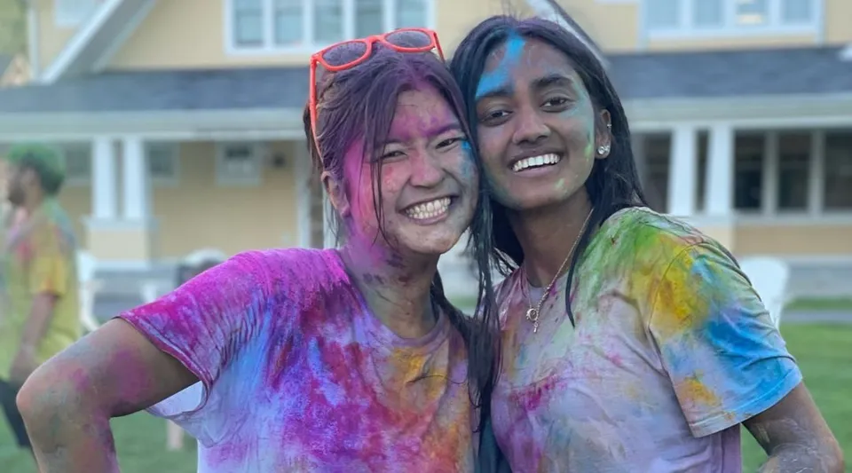 Due studentesse della The Williston Northampton School ridono in piedi davanti a un edificio con un'atmosfera festosa.
