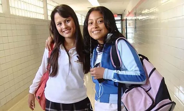 Dos alumnas están sonriendo en el pasillo del George Harvey Collegiate Institute y conversando.