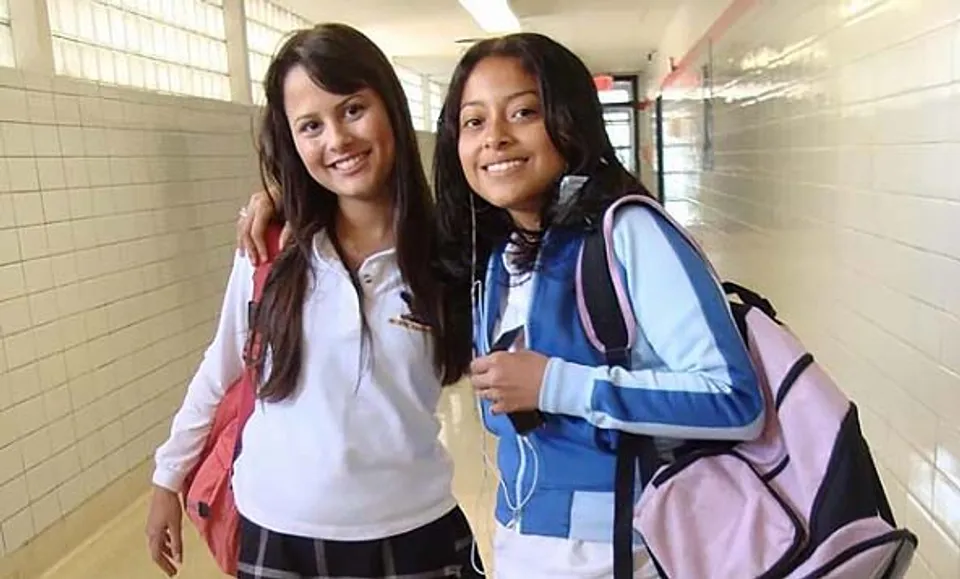 Due studentesse sorridenti chiacchierano nel corridoio del George Harvey Collegiate Institute.