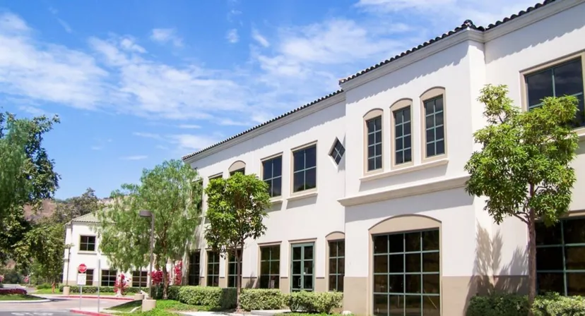 L'edificio a più piani con finestre ad arco e tetto in tegole del campus della JSerra Catholic High School è circondato da una verde vegetazione.