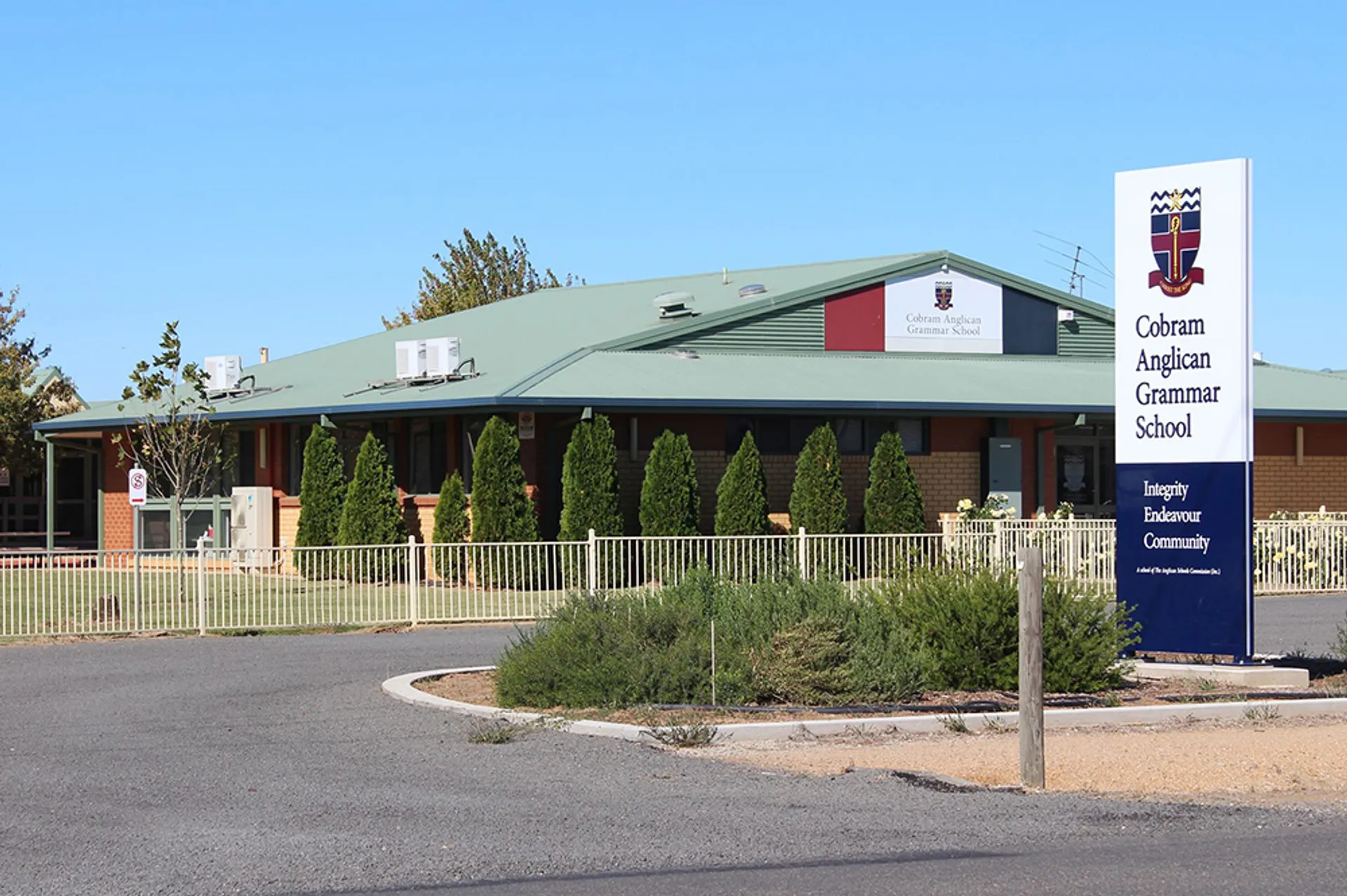 L'edificio a un piano della Cobram Anglican Grammar School con tetto verde e un grande cartello all'ingresso.