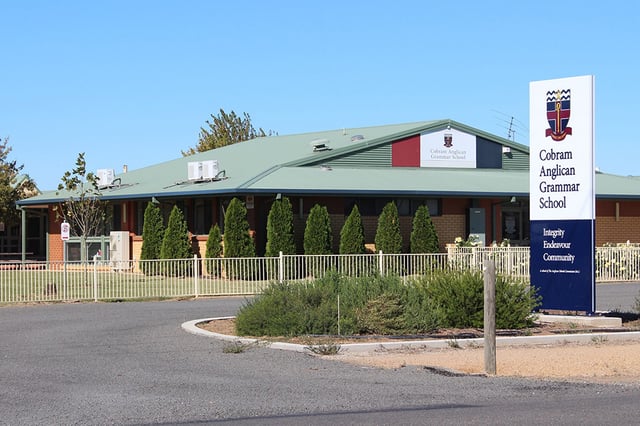 L'edificio a un piano della Cobram Anglican Grammar School con tetto verde e un grande cartello all'ingresso.
