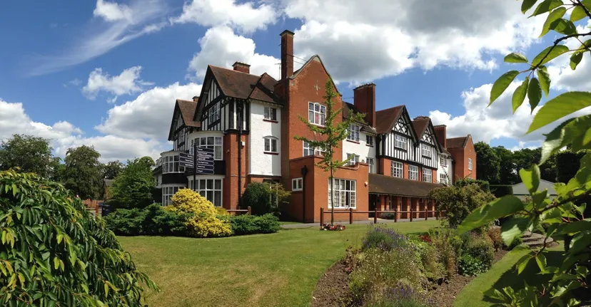 L'edificio in stile Tudor della Reed’s School è circondato da un giardino curato con prato e chiome verdi.