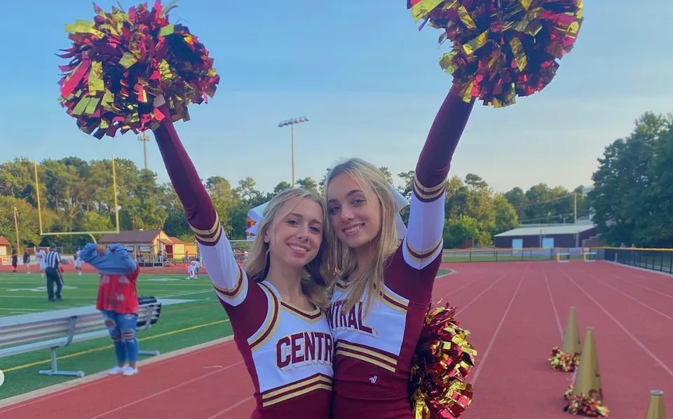 Due cheerleader della Central Regional High School sono sul campo sportivo davanti allo stadio con i pompon.