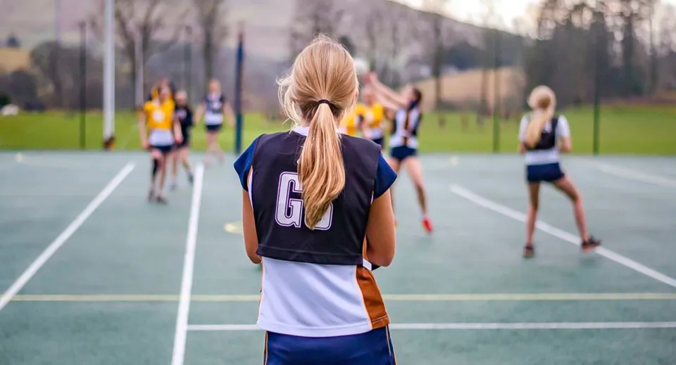 Studentesse della Sedbergh School giocano a netball su un campo sportivo all'aperto.