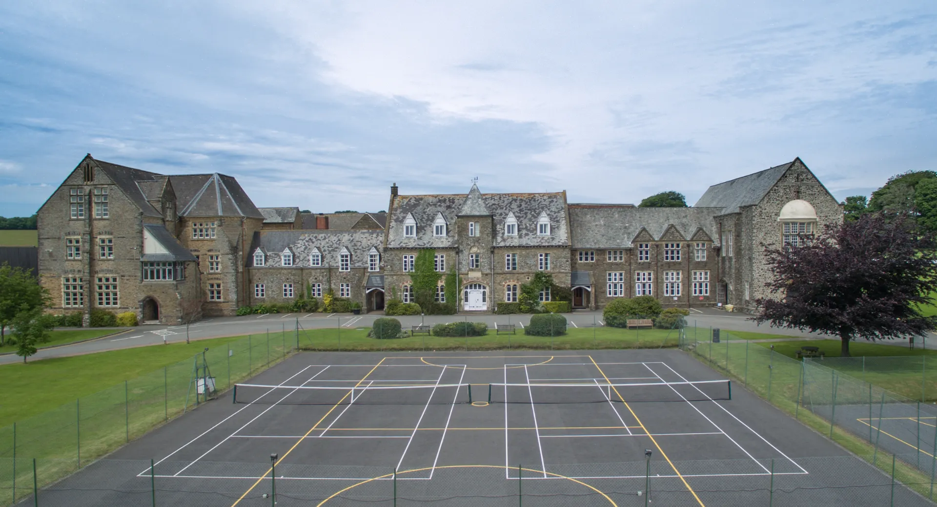 L'edificio storico della West Buckland School si trova dietro un prato ben curato e un campo da basket.