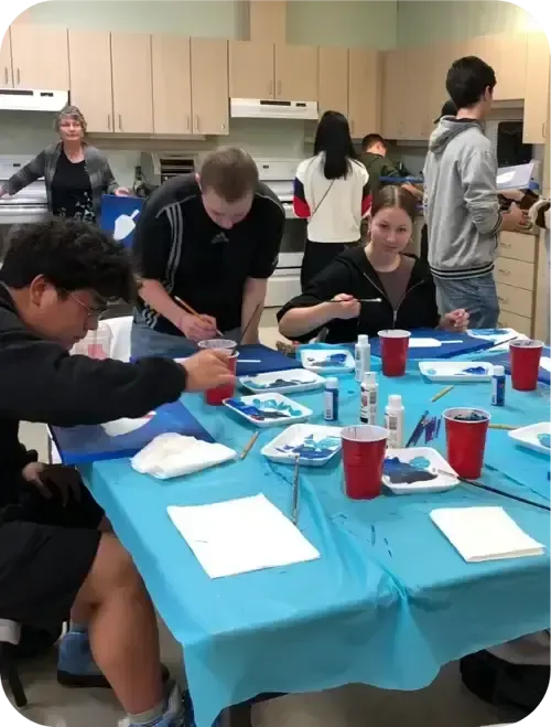 Alumnos sentados a la mesa pintando con acuarela en un taller de arte del instituto