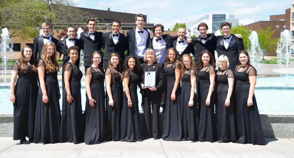 Un gruppo di studenti e studentesse della Marquette High School in abiti formali davanti a una fontana all'aperto.