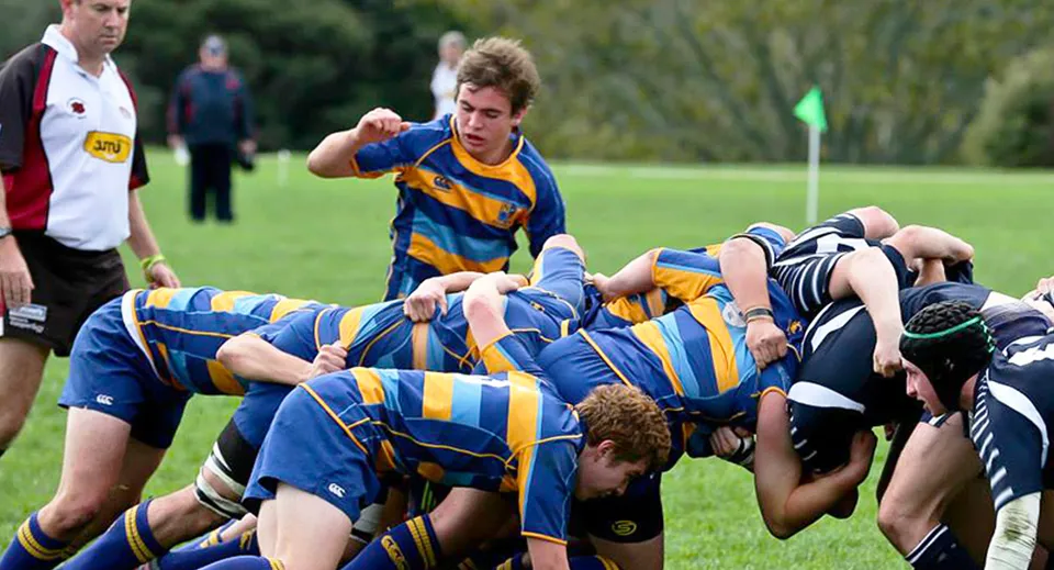 Un gruppo di giocatori di rugby del Northcote College lotta per il pallone in una mischia sul campo da gioco.