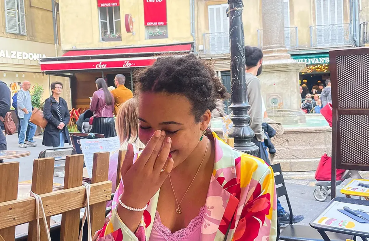 Ragazza ride seduta a un caffè all'aperto in una piazza cittadina