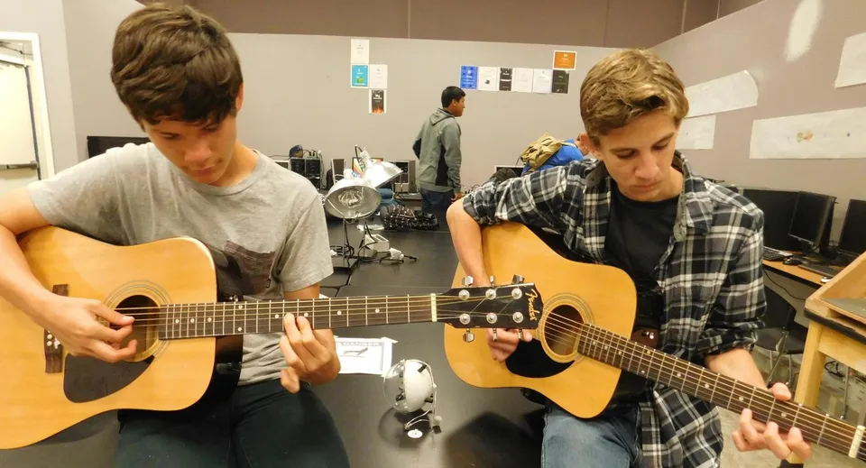 Due studenti suonano chitarre acustiche in un'aula di musica del Loyalist Collegiate & Vocational Institute.