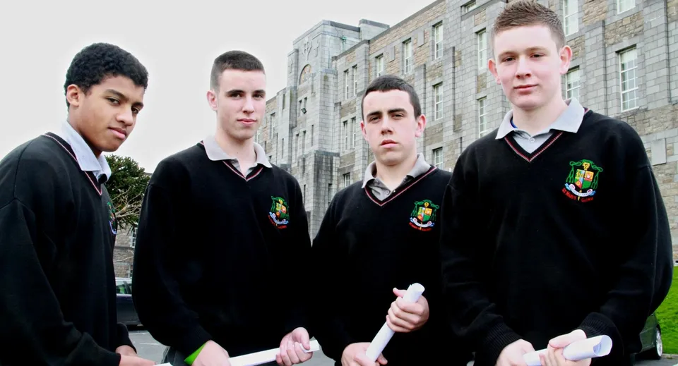 Quattro studenti in divisa scolastica si trovano davanti a un edificio in mattoni nel campus del St. Mary’s College Ballysadare.