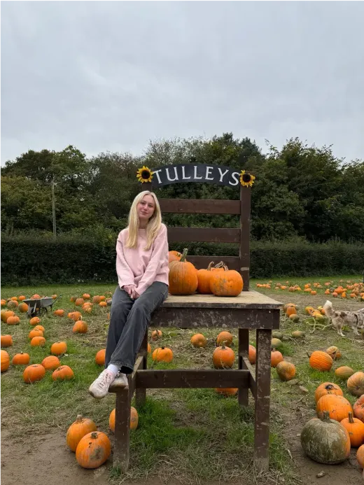 Ann-Kathrin sitzt auf einem riesigen Stuhl in einem Kürbisfeld in England