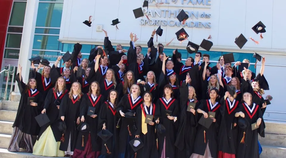 Un grande gruppo di diplomati e diplomate della National Sport School festeggia davanti a un edificio con l'insegna Antho Sports Guides.