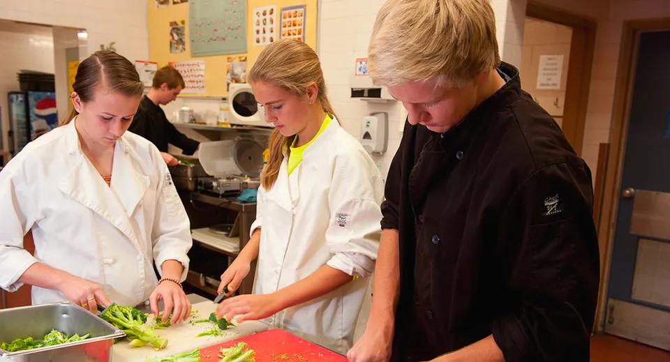Tre persone lavorano insieme in una cucina nel campus della South Delta Secondary School.