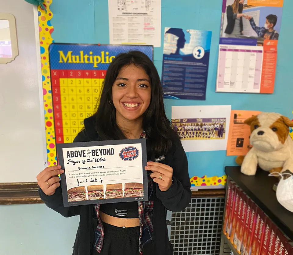 Una studentessa della Carl Schurz High School tiene in mano in un'aula un libro intitolato Above & Beyond: Players of the Week.