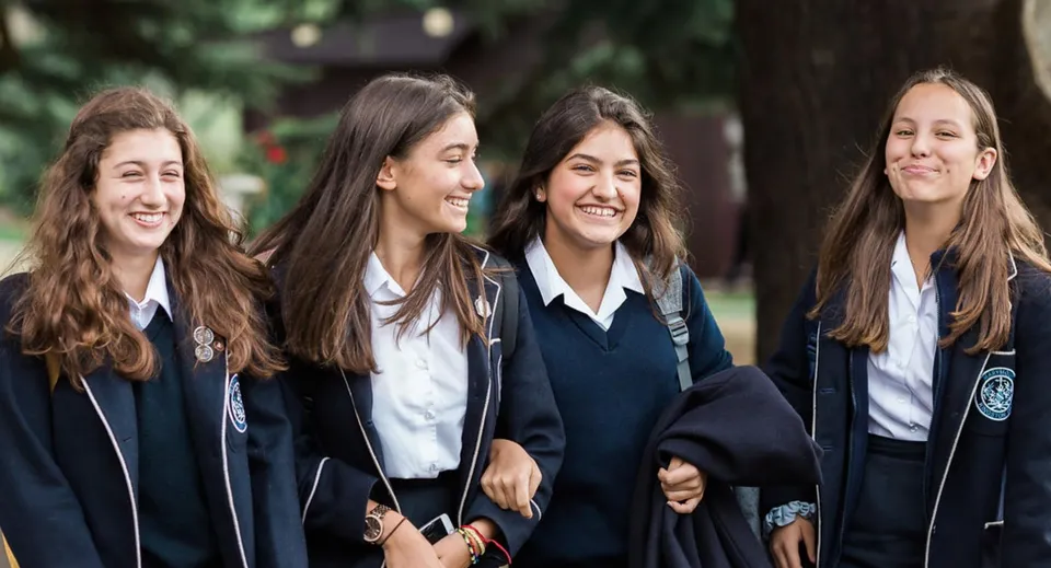 Quattro studentesse della Marymount International School sorridono insieme nell'area verde esterna della scuola.