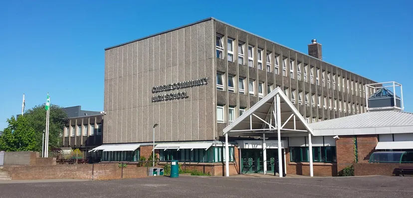 L'edificio principale moderno della Currie Community High School con un'area pavimentata adiacente e spazi verdi sullo sfondo.