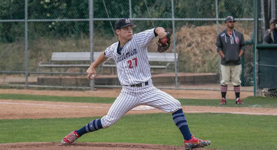 Un giocatore di baseball della Maranatha High School in maglia a righe lancia sul campo da baseball.