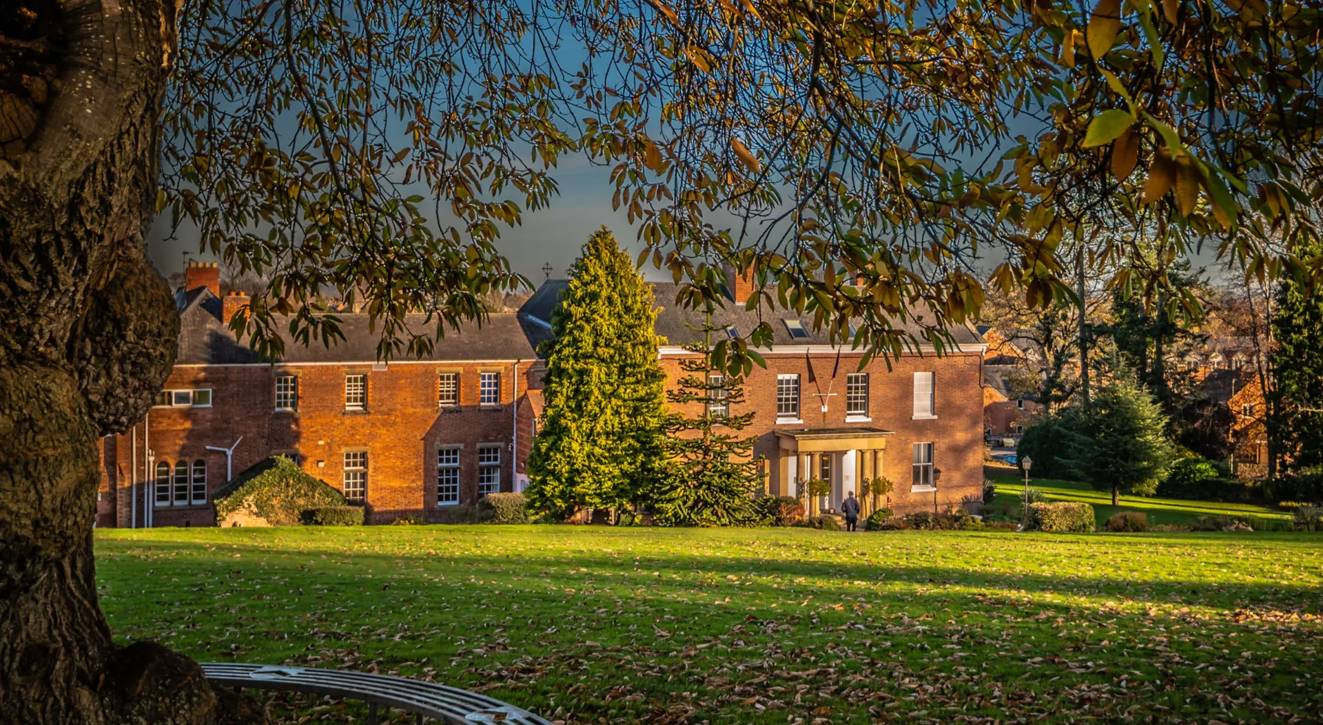 L'edificio in mattoni della Oswestry School è circondato da un verde paesaggio sotto un cielo azzurro e limpido.
