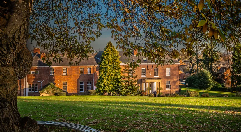 L'edificio in mattoni della Oswestry School è circondato da un verde paesaggio sotto un cielo azzurro e limpido.