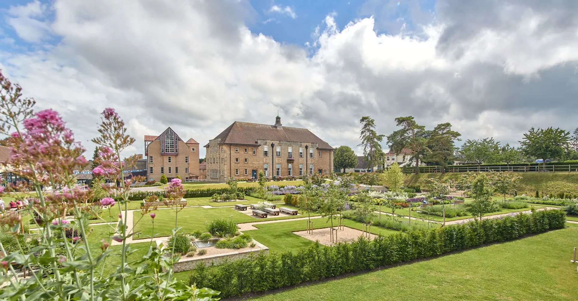 L'edificio storico della St. Mary's Calne è circondato da un giardino curato con fiori colorati e siepi potate.