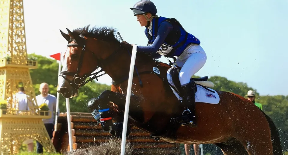 Una persona in tenuta da equitazione cavalca un cavallo marrone su un prato nel campus della Stowe School.