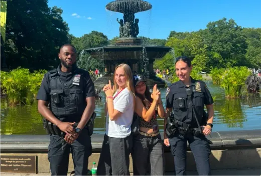 Due ragazze posano con due agenti di polizia davanti a una fontana a New York