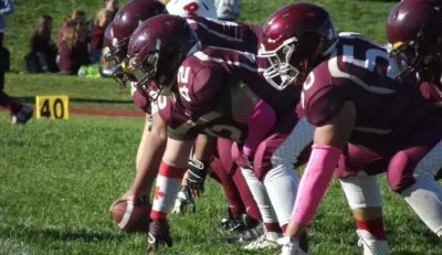 Un grupo de jugadores de fútbol americano con los colores de la M.M. Robinson High School está en un campo de fútbol con marcas.