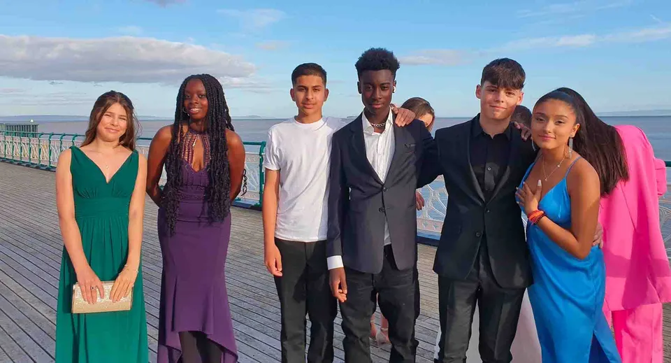 Un gruppo di studenti è in piedi su un pontile di legno sopra l'acqua all'interno del campus della Westbourne School.