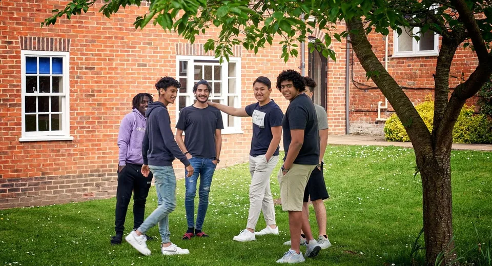 Un grupo de estudiantes está de pie en un área verde frente a un edificio de ladrillo en el campus de Padworth College.