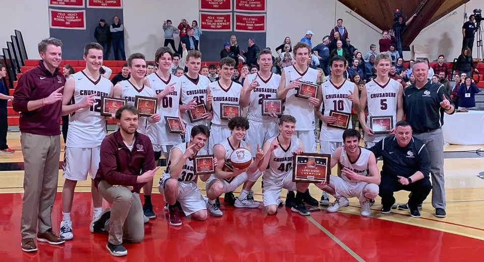 Studenti e allenatori della Groton-Dunstable Regional High School festeggiano la vittoria con i trofei sul campo da basket.