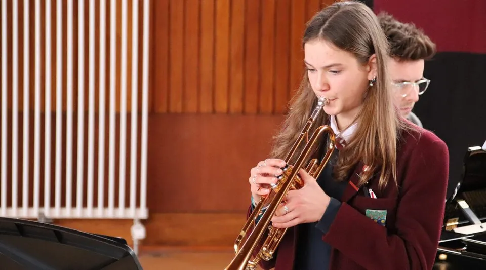 Una studentessa del George Watson’s College suona il trombone in una stanza con pareti rivestite in legno.